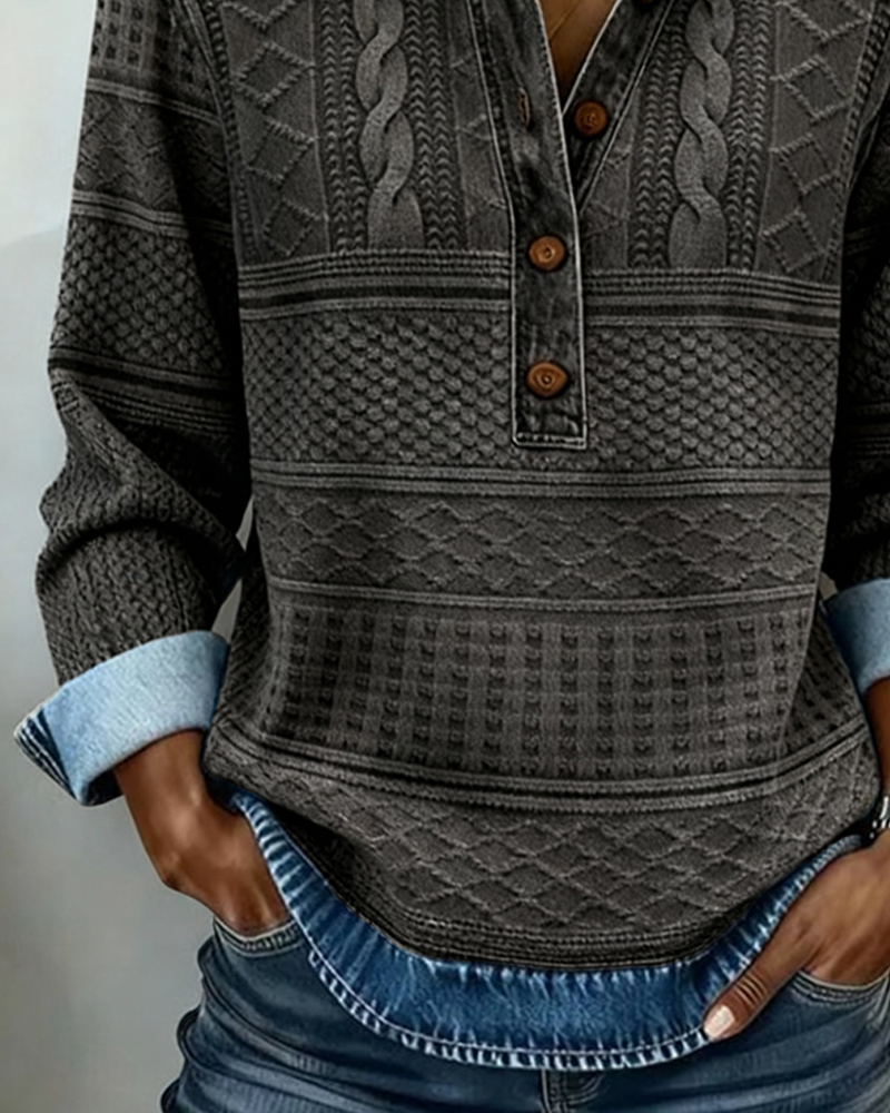 Nærbillede af den mørkegrå version med tre knapper, flettet strikmønster og denimkant forneden, hænderne i jeanslommerne. 7