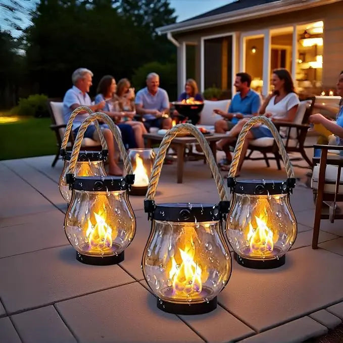Fire lanterner med dråber på glasset lyser på en terrasse, mens en gruppe mennesker sidder bagved 5