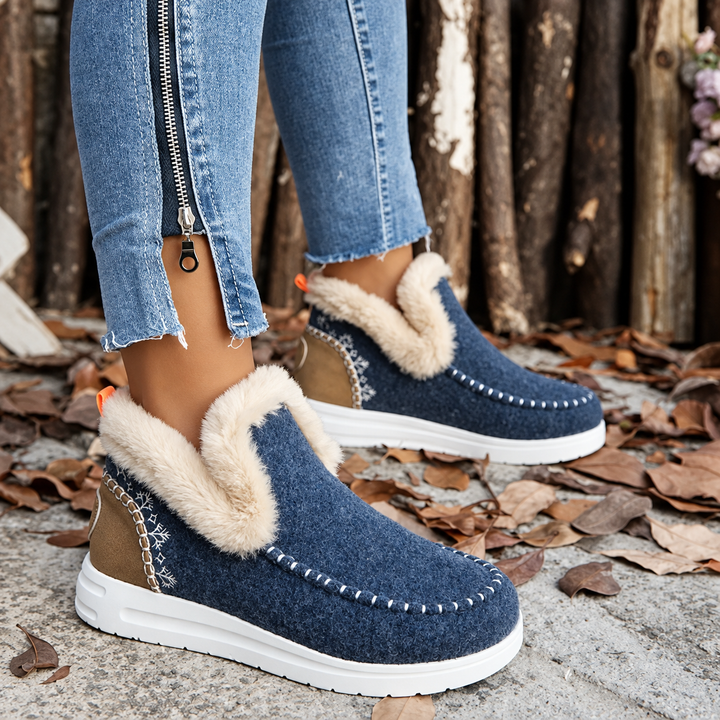 Mørkeblå sneakers med plyskant, broderi og hvid sål, båret med jeans med lynlås ved anklen. 10