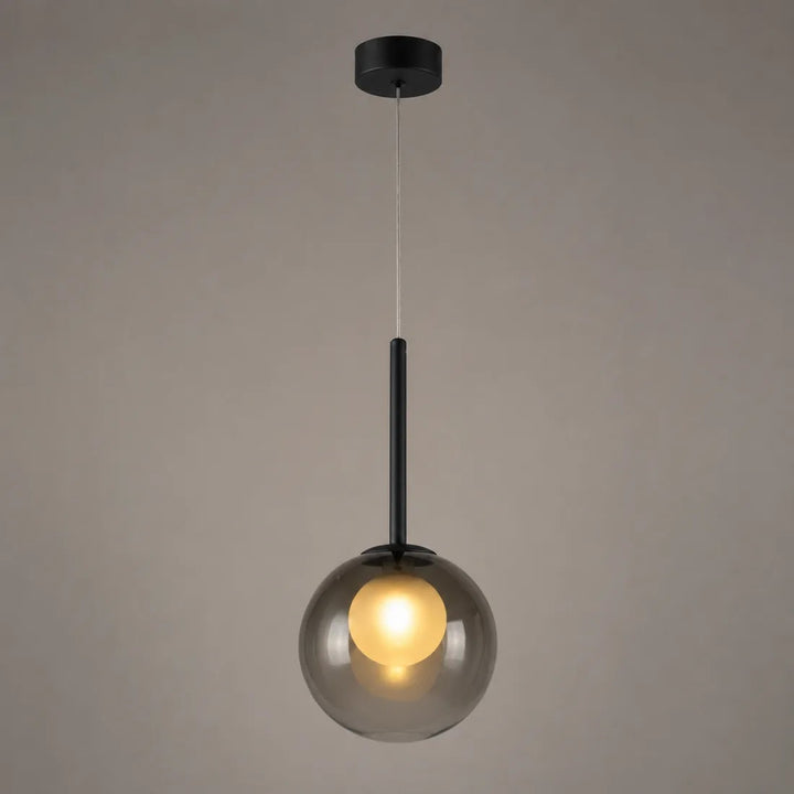 Tændt røggrå glaskuglelampe med sort stang, fotograferet foran en grå væg 10