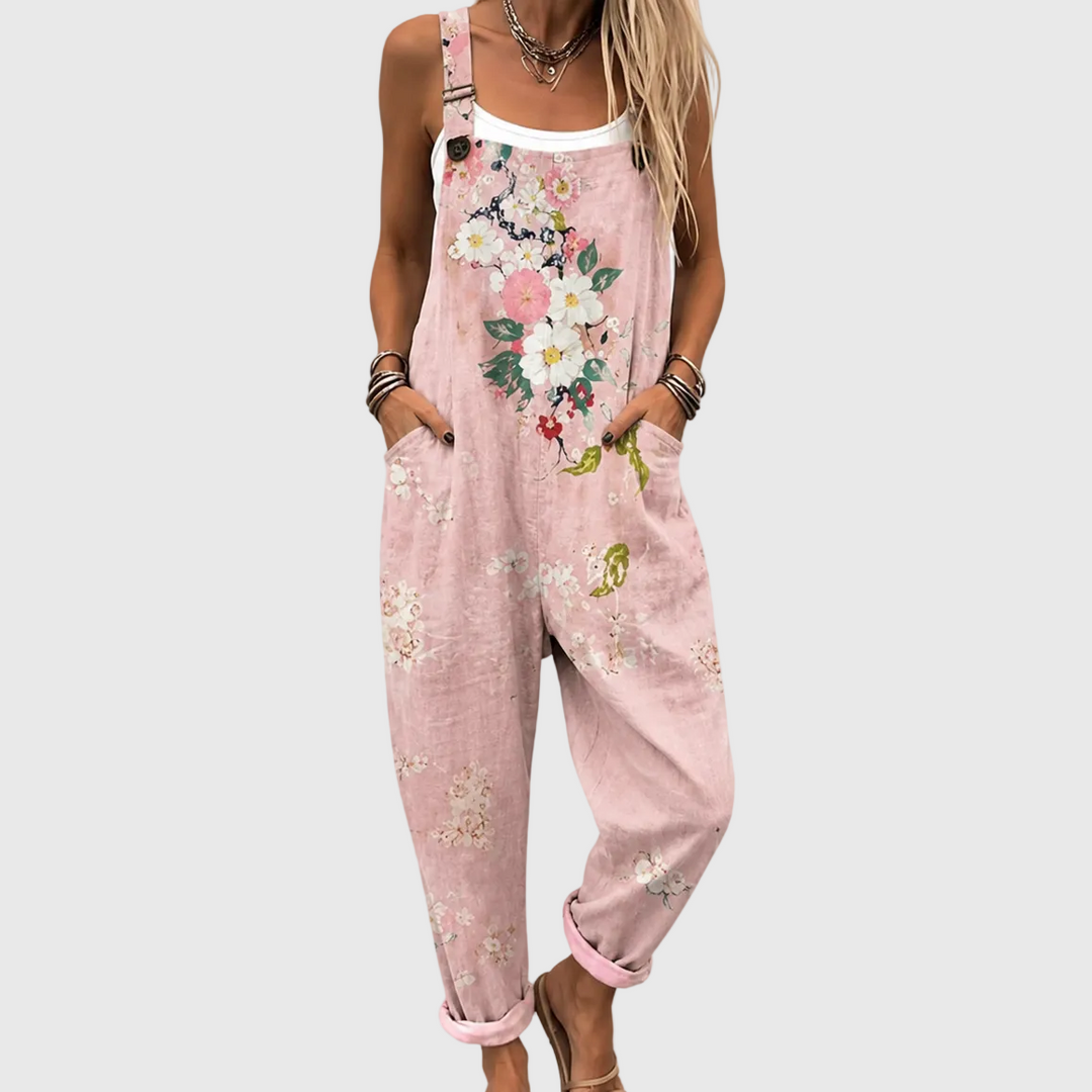 Nærbillede af modellen forfra i de lyserøde overalls med store blomster på brystet, hænderne i sidelommerne og oprullede ben. 1