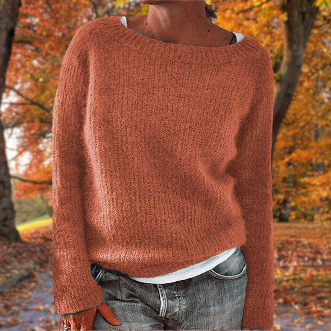 Kvinde i rustrød strikket sweater med rund hals, båret over hvid trøje og jeans i efterårsskov. 6