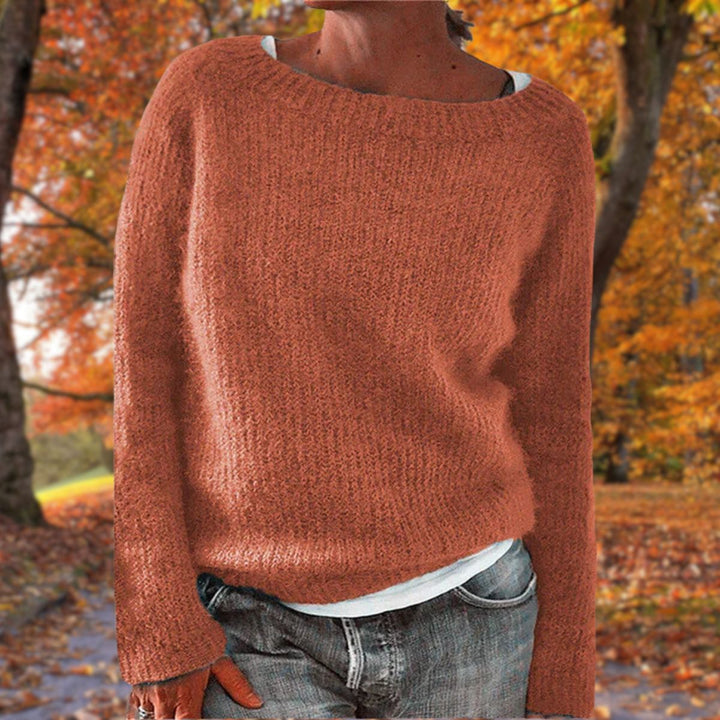 Kvinde i rustrød strikket sweater med rund hals, båret over hvid trøje og jeans i efterårsskov. 6