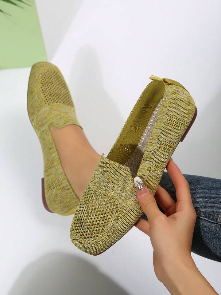 Gulgrønne mesh slip-on sko, hvor en hånd holder den ene sko og viser indersålen, på lys baggrund. 19