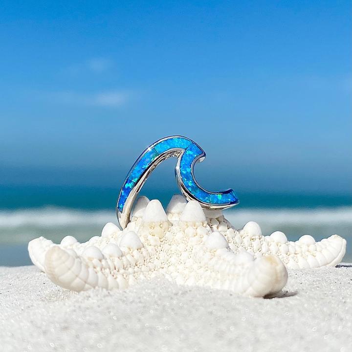Blauer Opal-Wellenring auf weißem Seestern am Strand, Schmuck, Sommer, Meer, Himmel.