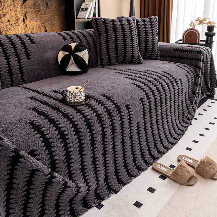 Sofa med mørkegråt betræk med sorte takkede striber, puder og kaffekop på sædet 13