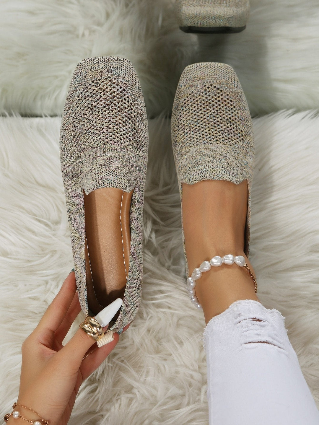 Ovenfra: en hånd holder den ene beige strikkede slip-on sko med hulmønstret mesh, mens den anden sidder på en fod med perlebesat ankelkæde. 21