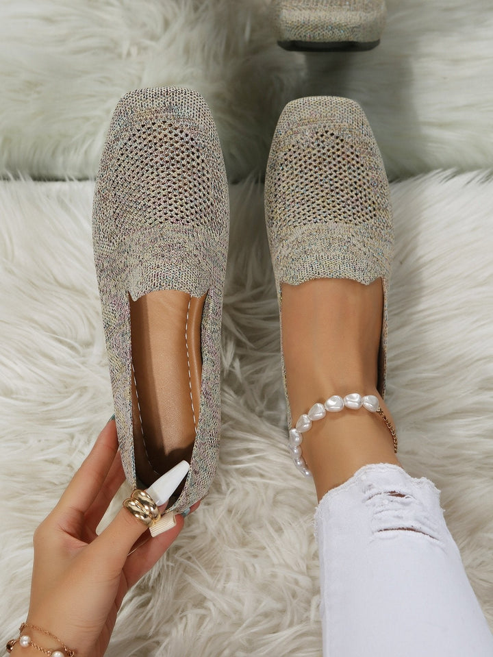 Ovenfra: en hånd holder den ene beige strikkede slip-on sko med hulmønstret mesh, mens den anden sidder på en fod med perlebesat ankelkæde. 21