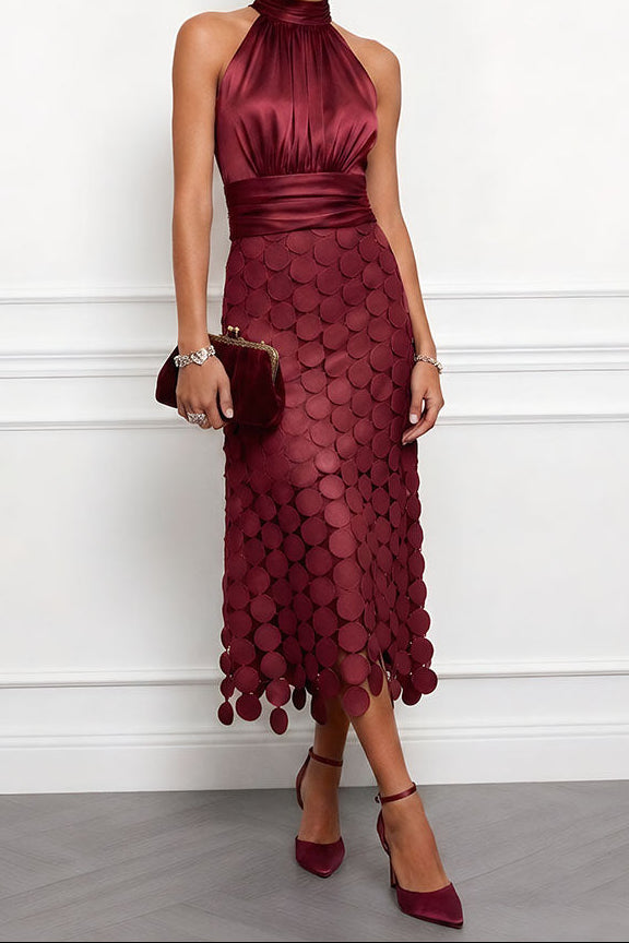 Model i vinrød satinkjole med haltertop og skørt af runde skiver, med lille bordeaux clutch og matchende pumps. 5