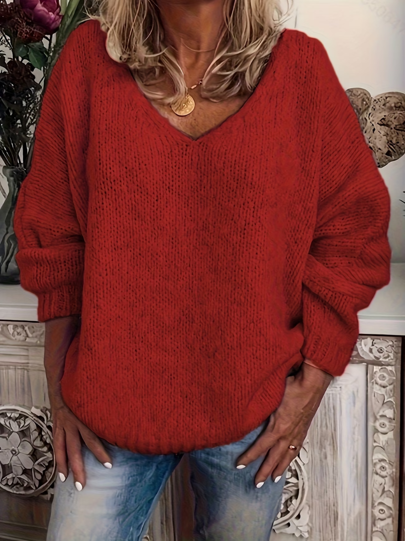 Kvinde i rød grofstrikket trøje med V-hals og brede ærmer med ribkant, kombineret med jeans. 5