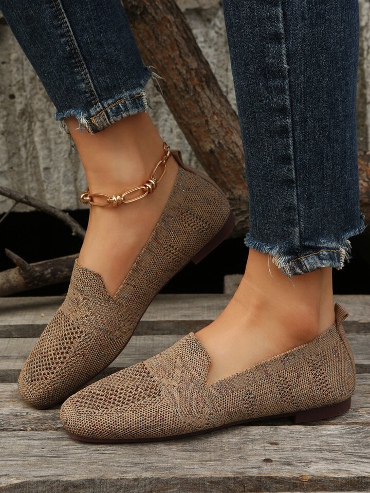Brune strikkede slip-on sko med hulmønster set fra siden, båret af model i jeans med guldkæde om anklen. 5