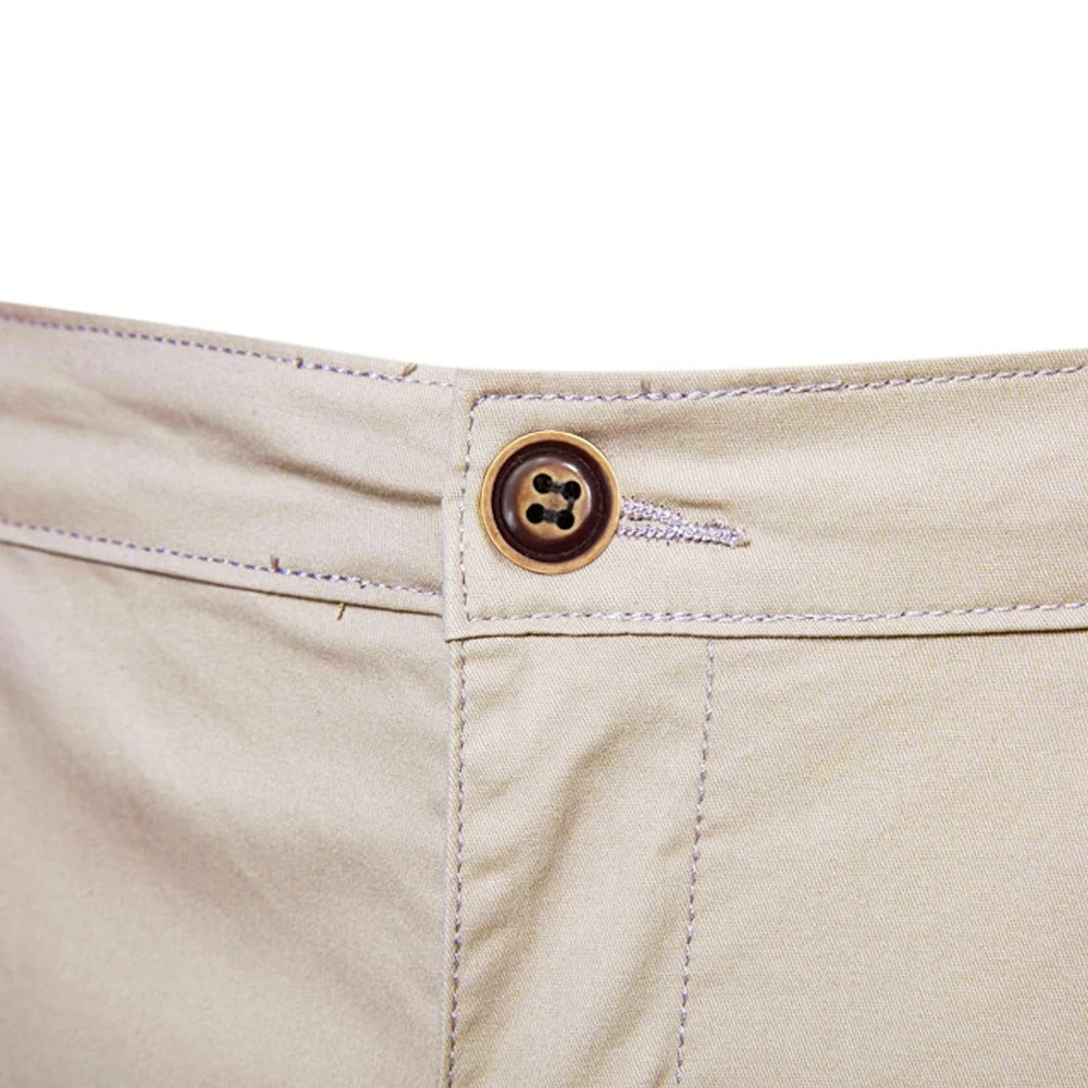 Nærbillede af linningen på beige shorts med brun knap, knaphul og kontrastsyninger. 5