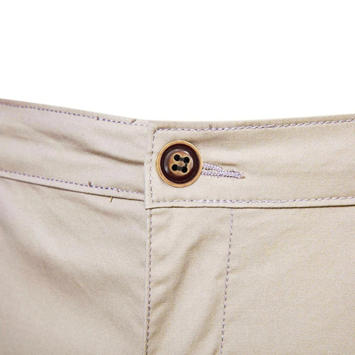 Nærbillede af linningen på beige shorts med brun knap, knaphul og kontrastsyninger. 5