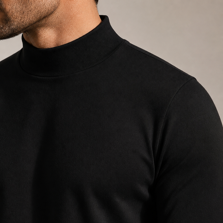 Detaljebillede af den sorte høje krave og skulderen set på en model, der viser stoffets struktur og pasform. 6