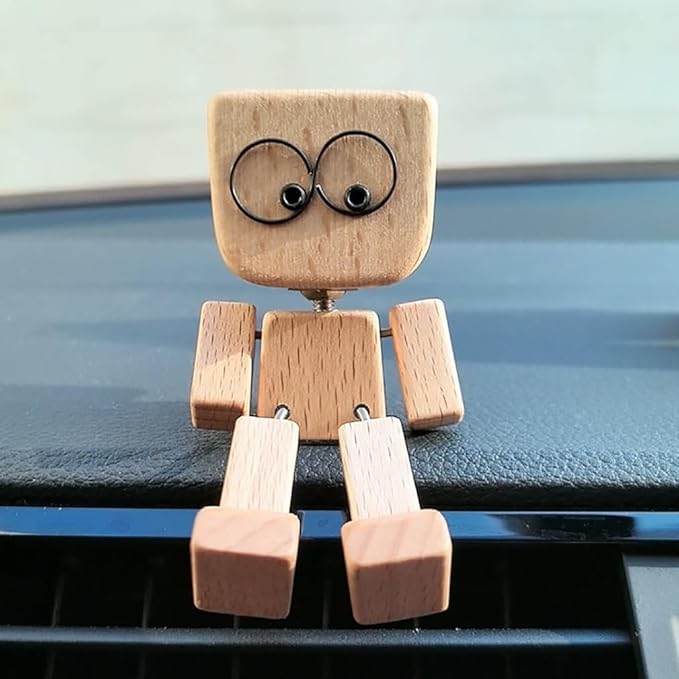 Træfigur med store runde øjne set forfra, siddende på instrumentbrættet i en bil med benene ned over luftdysen. 14
