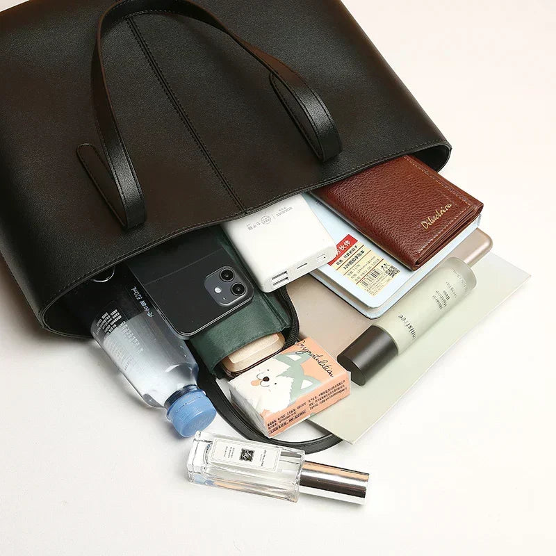 Sort totebag med telefon, flaske, pung, parfume og andre ting ved siden af 6