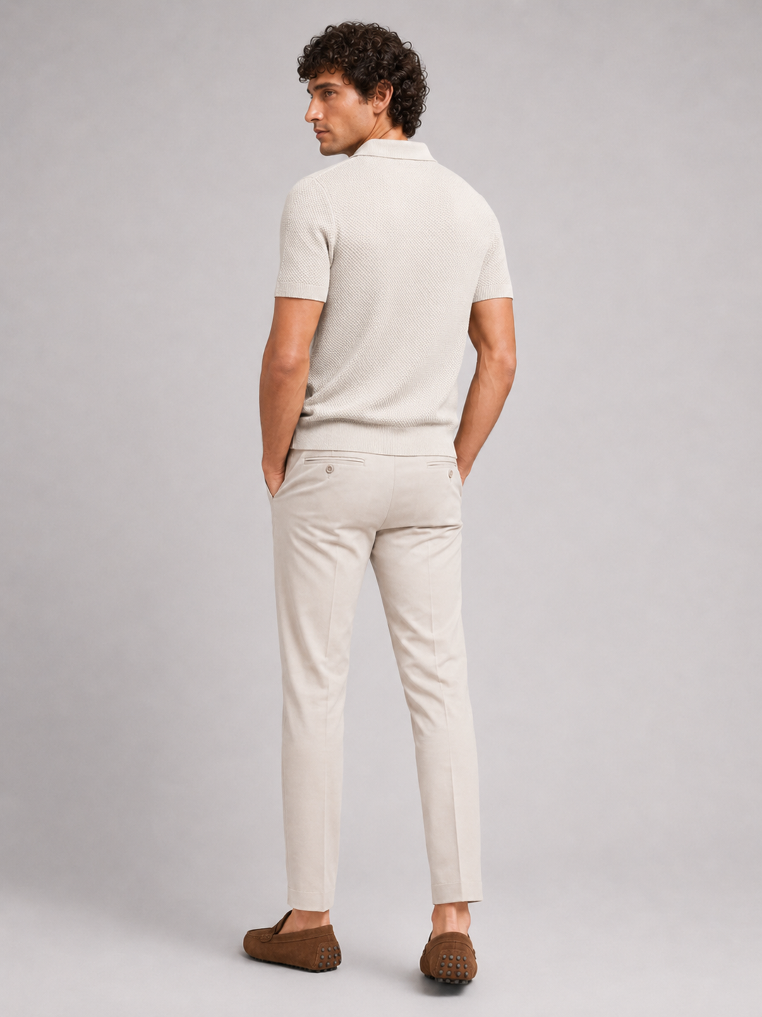 Beige strikpolo set bagfra på model med lyse bukser og brune loafers 19