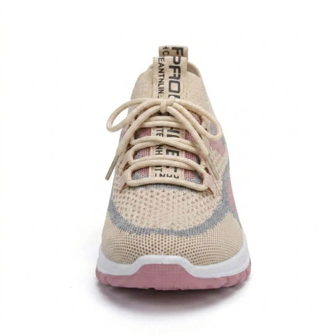 Beige sneaker med lyserøde og blå detaljer set direkte forfra, med snøring, mesh-overdel og lyserød sål. 35