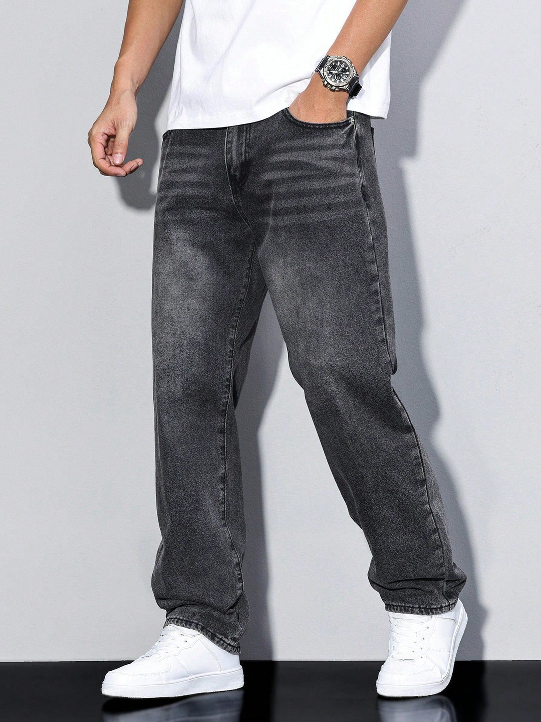 Sortgrå vaskede jeans med lige ben set skråt forfra på model, hånd i lommen, hvide sneakers. 10