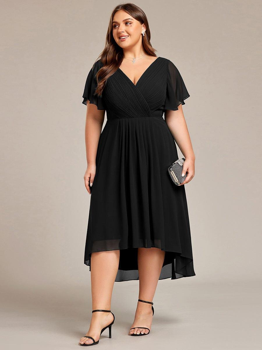 Sort kjole i plussize set forfra på model med lille glitrende clutch og sorte sandaler. 30