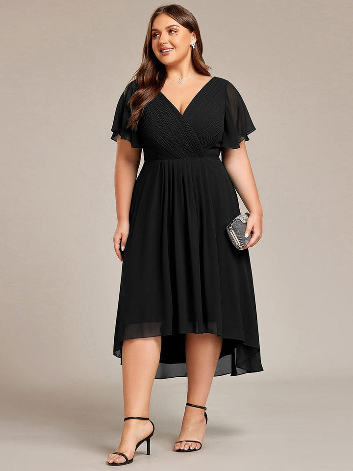 Sort kjole i plussize set forfra på model med lille glitrende clutch og sorte sandaler. 30