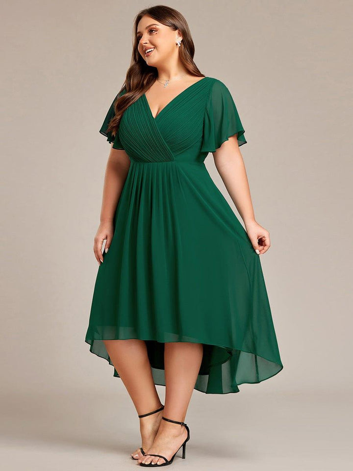Mørkegrøn kjole i plussize set fra siden på smilende model, der holder let i nederdelen. 39