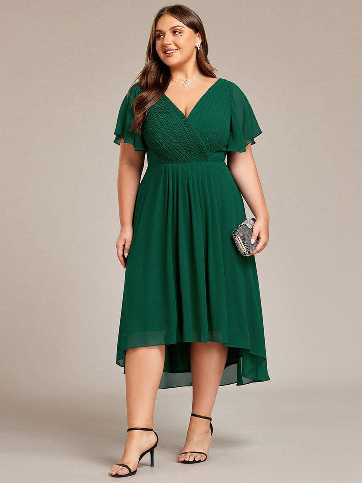 Mørkegrøn kjole i plussize set forfra på model med lille glitrende clutch og sorte sandaler. 40