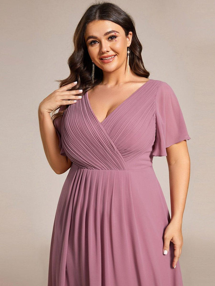Nærbillede af den plisserede overdel med V-hals og flagrende ærme i mauve på plus size-model. 65