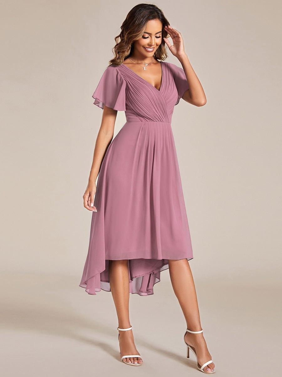 Kjolen i mauve set forfra på model med hånden ved panden, med asymmetrisk fald og plisseret overdel. 62
