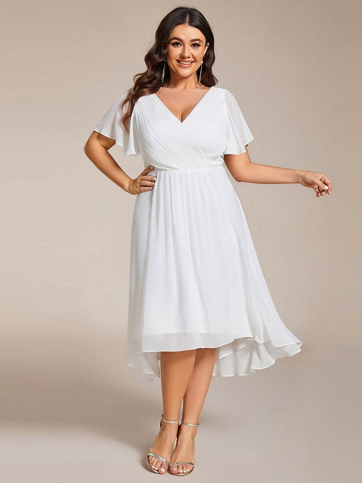 Plus size-model i hvid kjole med hånden på hoften, V-hals, flagrende ærmer og asymmetrisk fald. 73