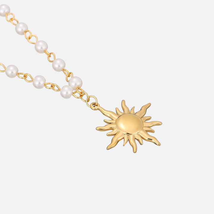 Skråt close-up af solvedhænget og perlekæden, der viser det blanke guld og de små perler tæt på. 2