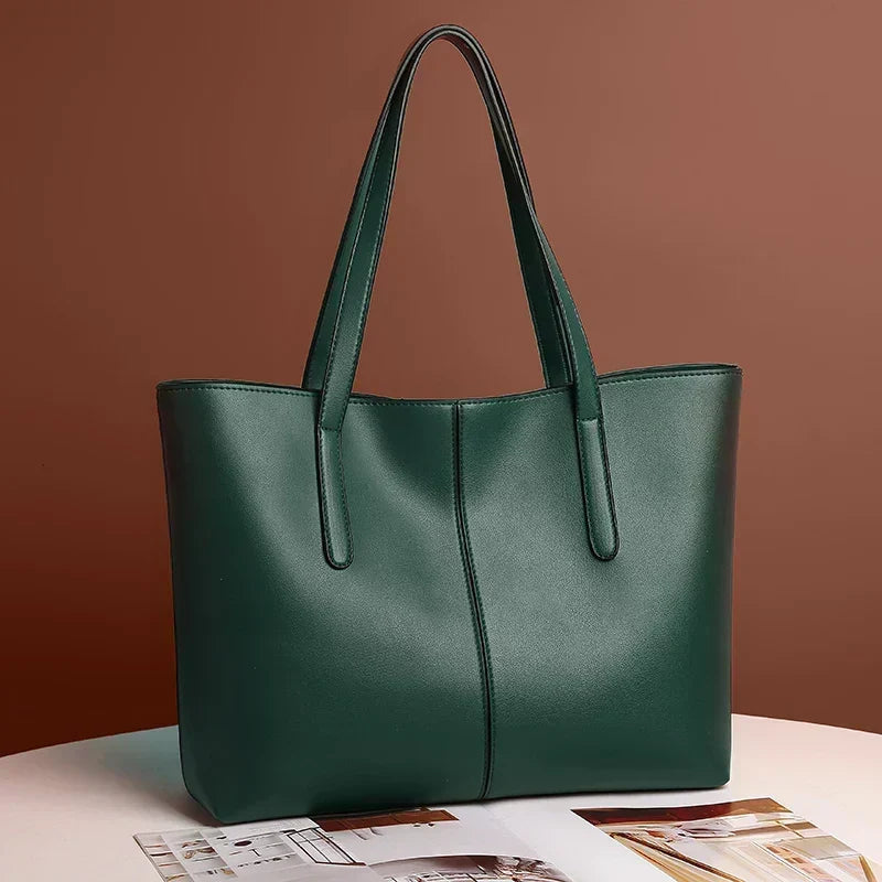 Mørkegrøn totebag med lange stropper stillet på et bord foran brun baggrund 4