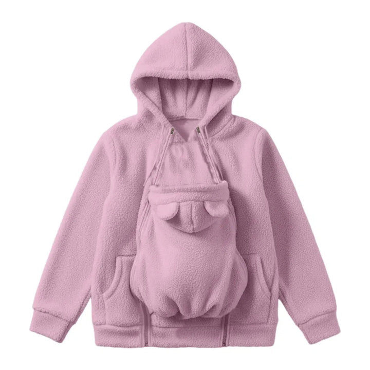 Lyserød hættetrøje i sherpa-fleece set forfra som flat lay, med babybærepanelet med bjørneører lynet fast på maven. 1
