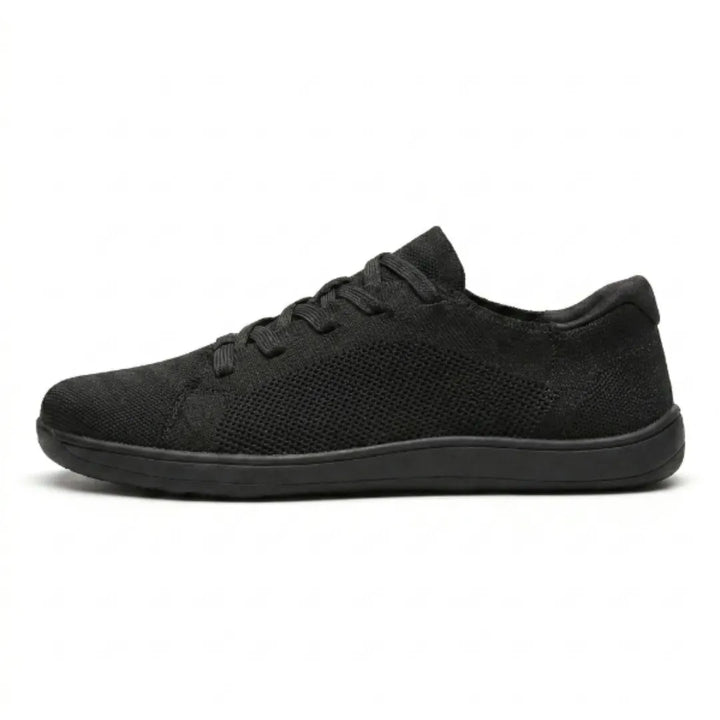Sort sneaker i åndbart strikmesh med sort flad sål, set fra siden på hvid baggrund. 10