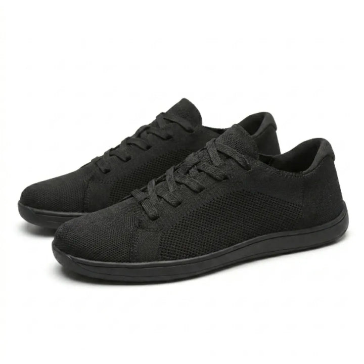 Et par sorte strikmesh-sneakers med snørebånd og flad sål, set på skrå forfra på hvid baggrund. 16