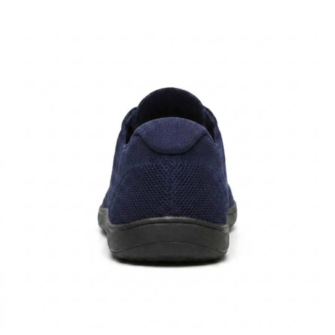 Marineblå mesh-sneaker med sort sål set bagfra med hælkappe og strikket overdel. 27