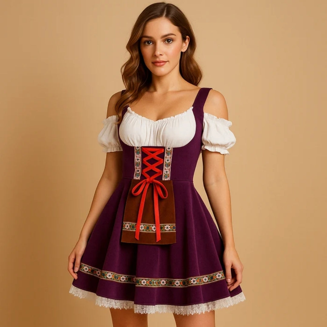 Model i lilla dirndl med blonde i bunden, rød snøring, brun lommeforklæde-detalje og hvid bluse med afslappede skuldre. 2