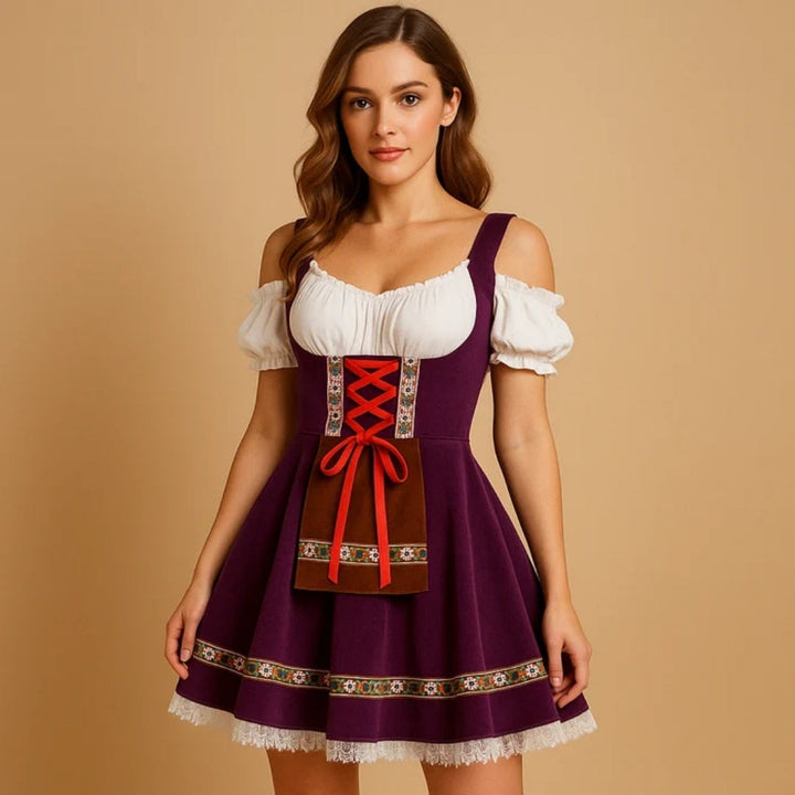 Model i lilla dirndl med blonde i bunden, rød snøring, brun lommeforklæde-detalje og hvid bluse med afslappede skuldre. 2