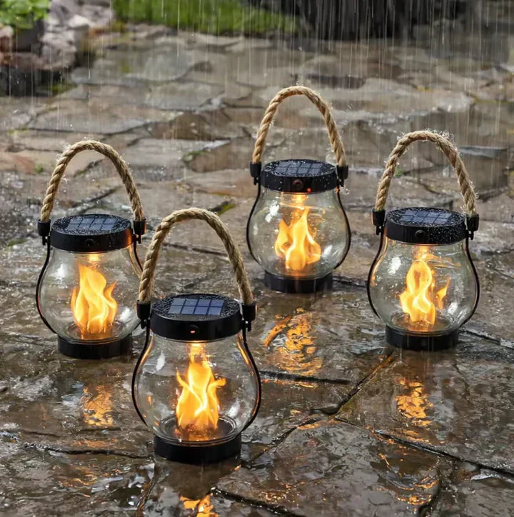 Fire lanterner med solcellelåg og flammeeffekt lyser på våde fliser midt i et regnvejr 3