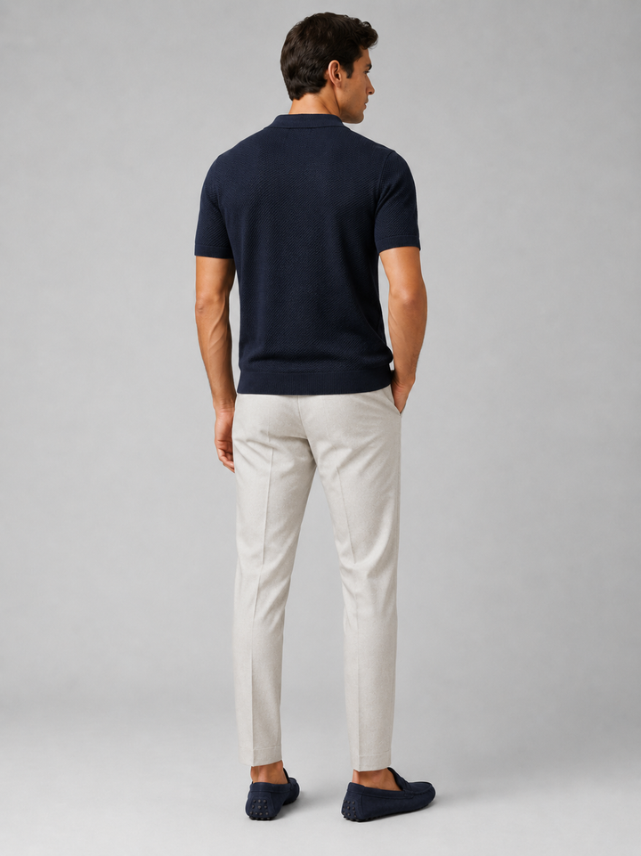 Model i marineblå strikpolo set bagfra med lyse bukser og marineblå loafers 38