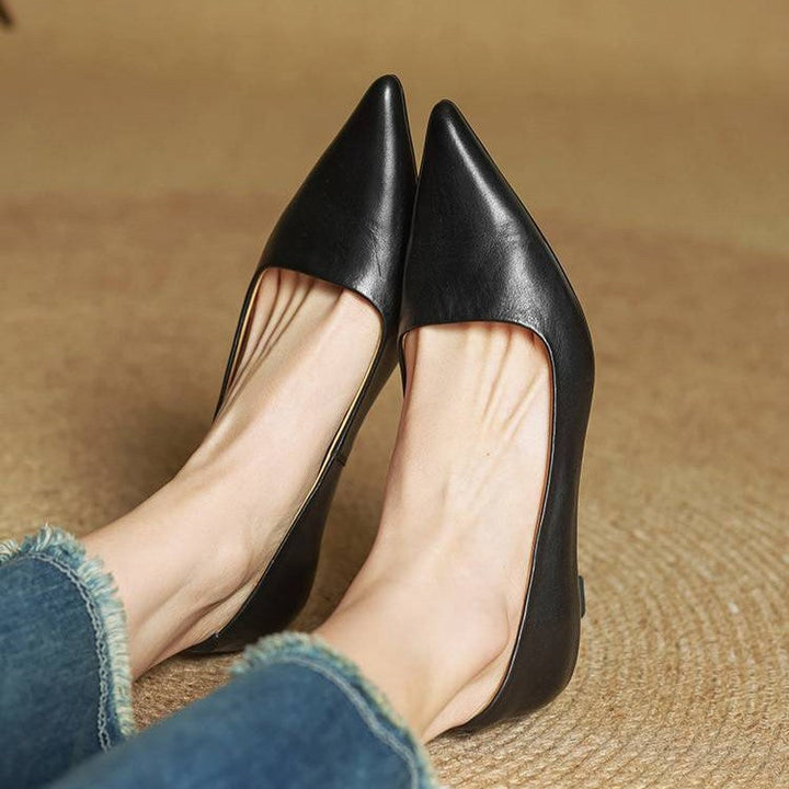 Nærbillede af de spidse tæer på sorte pumps båret af model i jeans, siddende 15