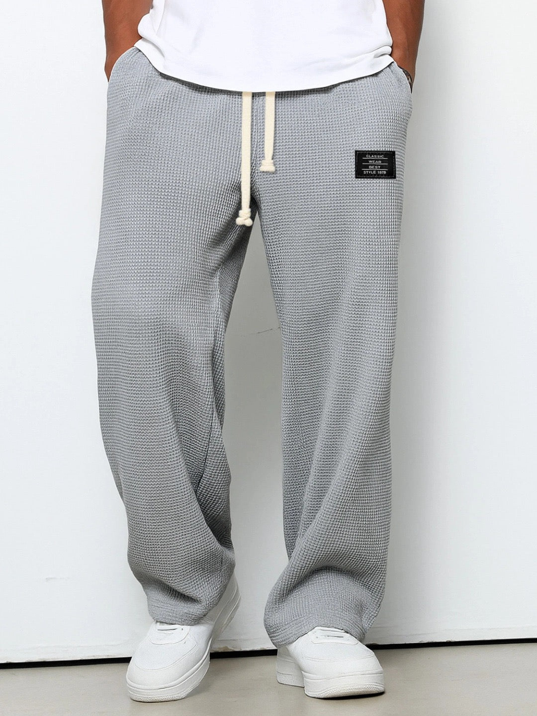 Mellemgrå vaffelstrikbukser med vide ben og elastisk talje med snøre, båret med hvid t-shirt og hvide sneakers. 3