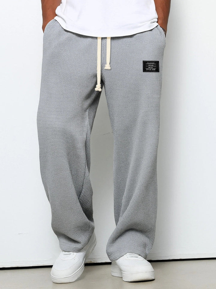 Mellemgrå vaffelstrikbukser med vide ben og elastisk talje med snøre, båret med hvid t-shirt og hvide sneakers. 3