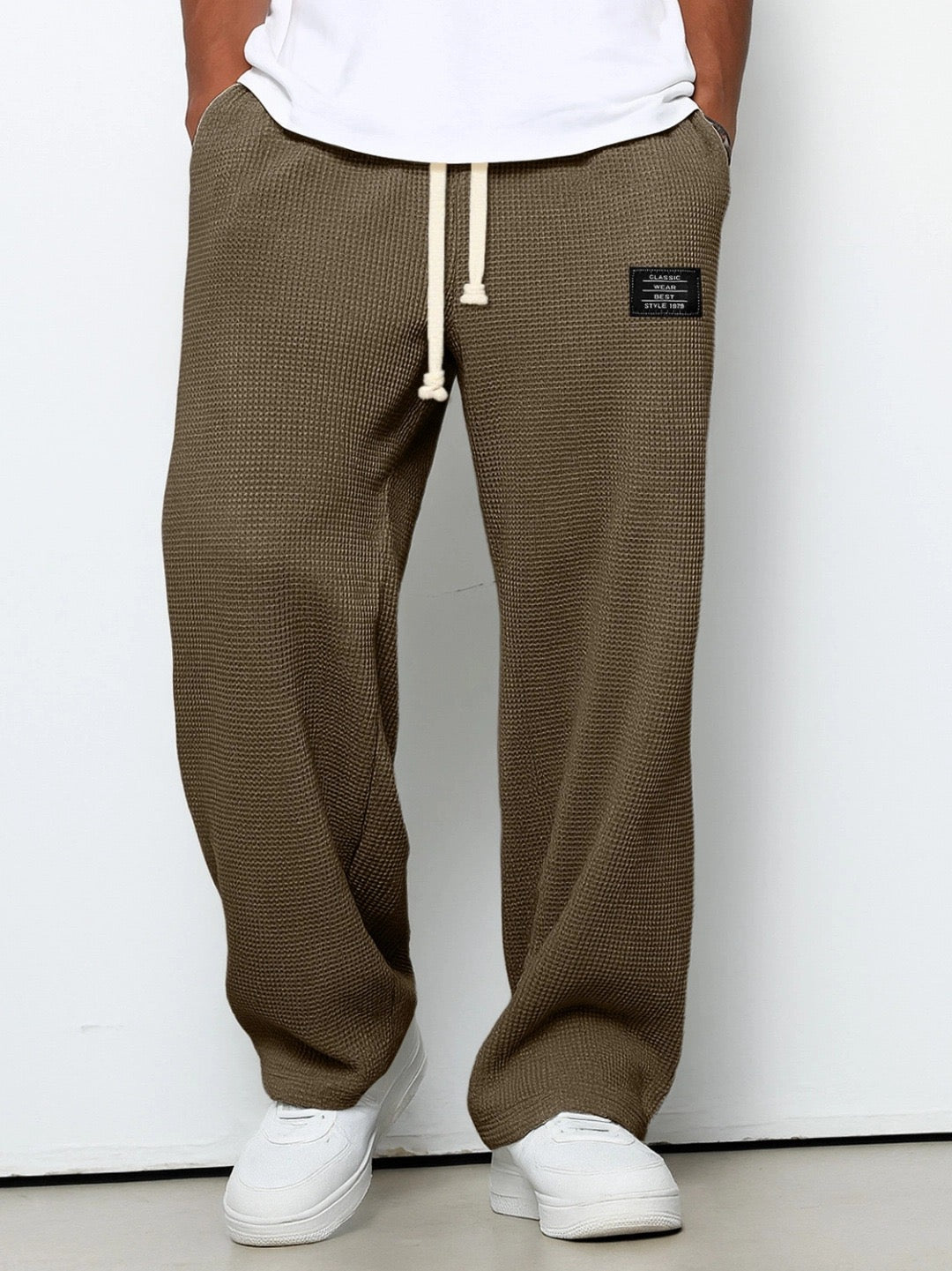 Brune vaffelstrikbukser med vide ben og snørebånd i taljen, båret af en model med hvid t-shirt og sneakers. 5