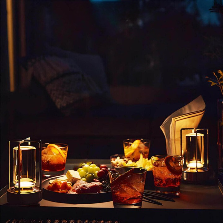 To tændte lamper på et mørkt bord med drinks, frugt og snacks til en hyggelig aften. 6