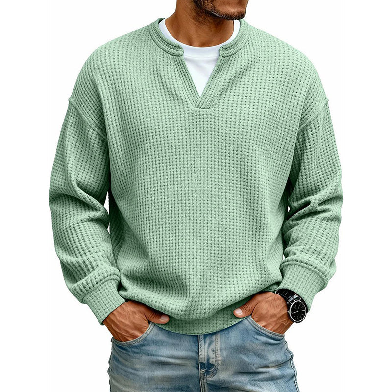Model i lysegrøn vaffelstrikket trøje med lagdelt krave, hvid T-shirt under og hænderne i jeansfladerne, på hvid baggrund. 4