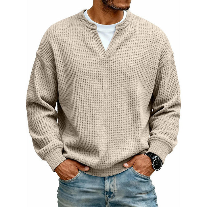 Beige vaffelstrikket trøje med lagdelt krave, båret over hvid T-shirt og med hænderne i jeanslommerne. 5