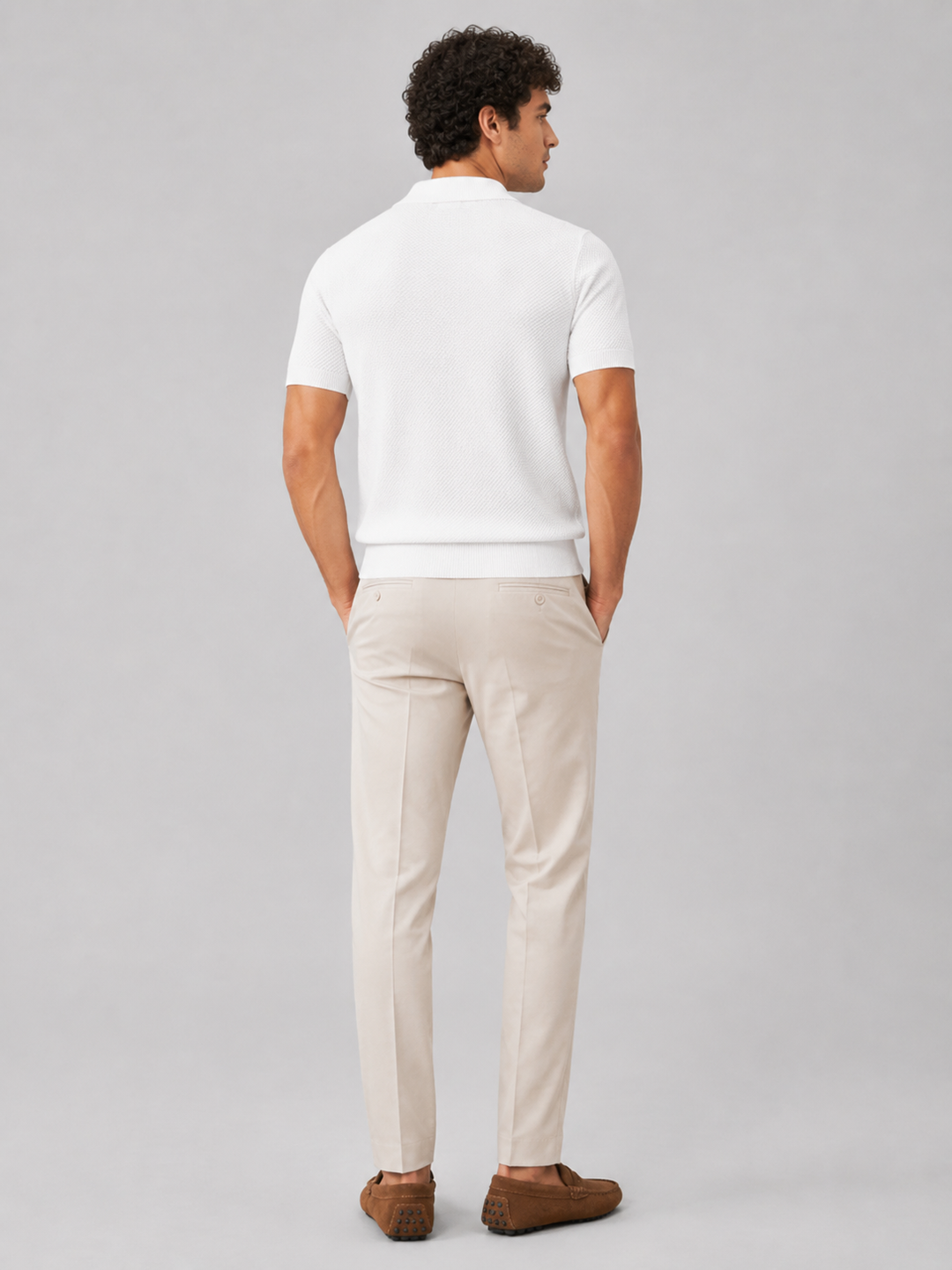 Model i hvid strikpolo set bagfra med beige bukser og brune ruskindsloafers 33