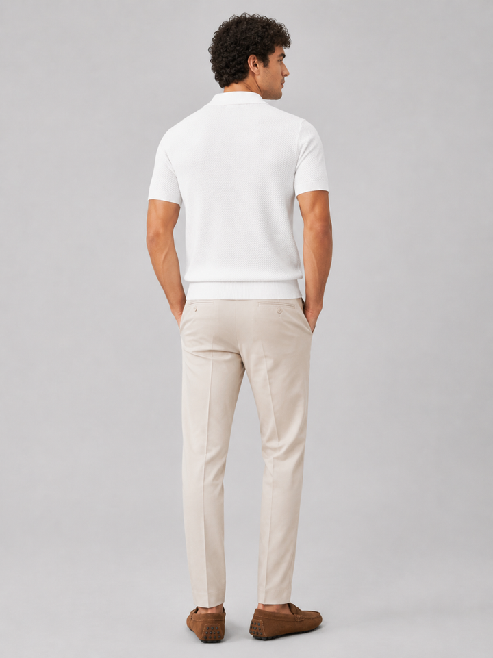 Model i hvid strikpolo set bagfra med beige bukser og brune ruskindsloafers 33