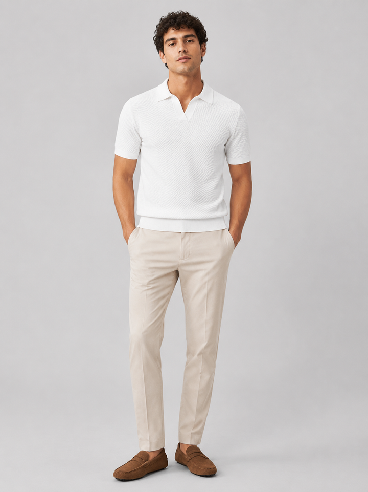 Helfigur af model i hvid strikpolo med beige bukser og brune ruskindsloafers, set forfra 32